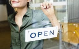 Woman placing open sign on glass door